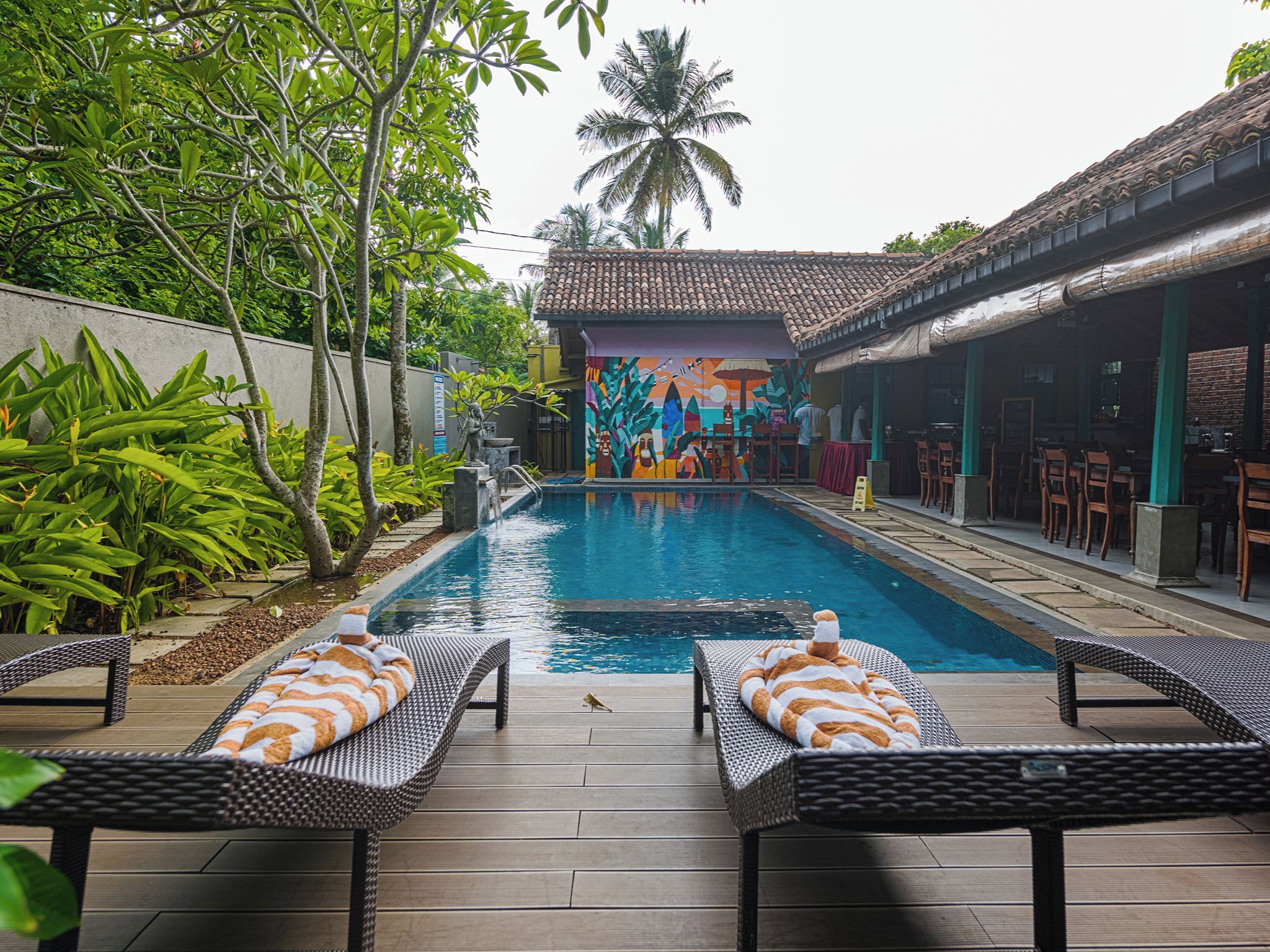 A pool area with lounge chairs and a mural.