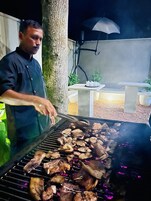 Una persona asando carne al aire libre de noche.