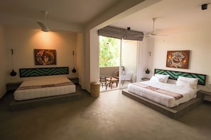Quarto de hotel com duas camas, ventiladores de teto, obras de arte e vista para o exterior.