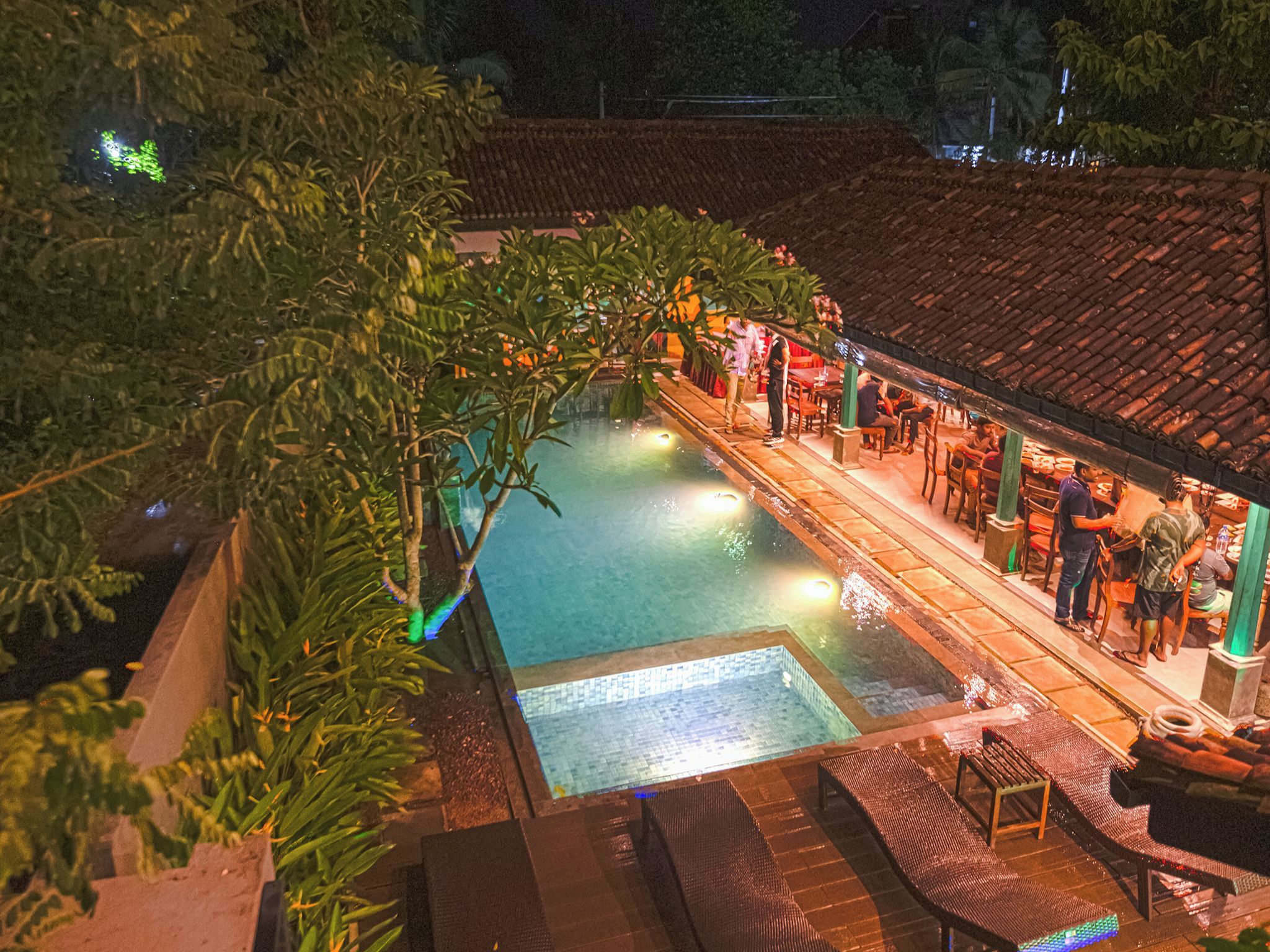 Un espace piscine sur le toit, doté d’une terrasse carrelée, de chaises longues et d’un bar.