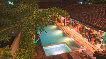 A rooftop pool area with a tiled deck, lounge chairs, and a bar area.