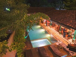Un espace piscine sur le toit, doté d’une terrasse carrelée, de chaises longues et d’un bar.