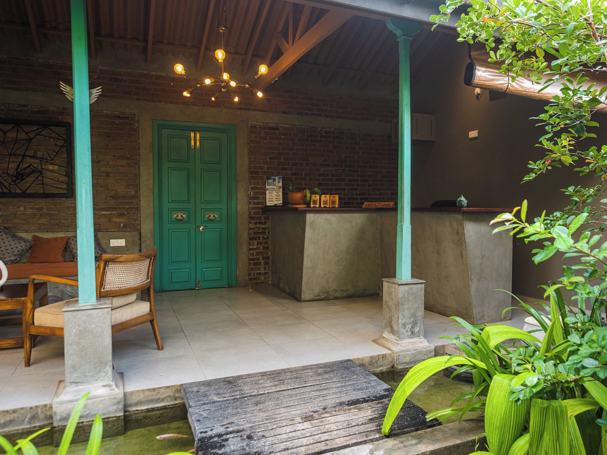 A cozy outdoor seating area with a brick wall, a green door, and a hanging light fixture.