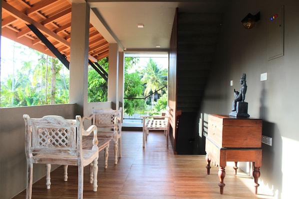 Quarto com piso de madeira, móveis brancos e vista para o verde lá fora.