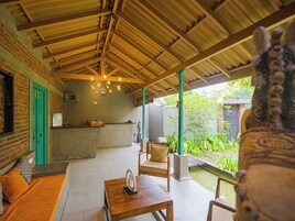 Un espacio de estar techado al aire libre con pared de ladrillo, un mostrador de recepción y vistas a un jardín.