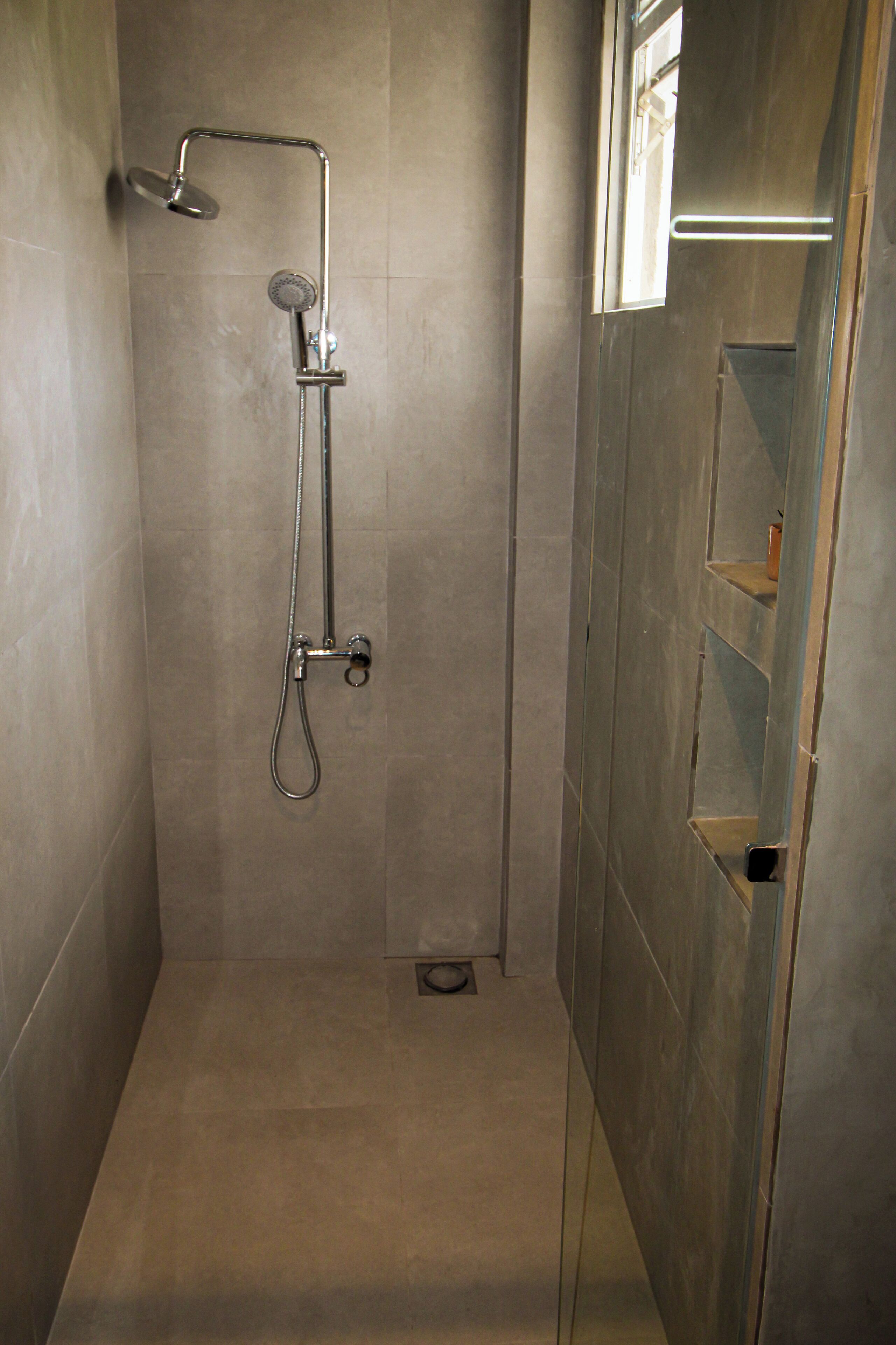 A modern shower with a handheld showerhead and a wall-mounted faucet.