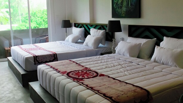 A hotel room with two beds, a large window with a view of greenery, and a painting on the wall. - The Chariot Hikkaduwa (Hikkaduwa)