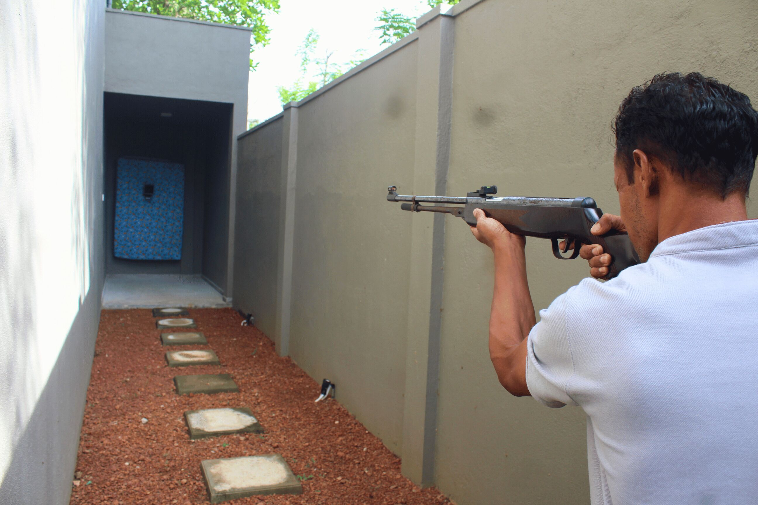 A person aiming a firearm at a target in an outdoor shooting range.