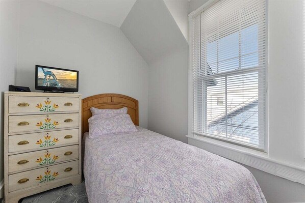 A bedroom with a bed, a dresser with drawers, a television on the dresser, and a window with blinds. - Spacious 4BR Home Walk to Beach, Bay, Boardwalk (Wildwood)