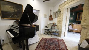 Een woonkamer met een vleugelpiano, een kamerbreed tapijt met dessin, een gitaar en een gezellige zithoek.
