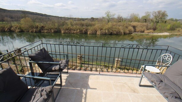 Een balkon met buitenmeubilair, met uitzicht op een rivier.