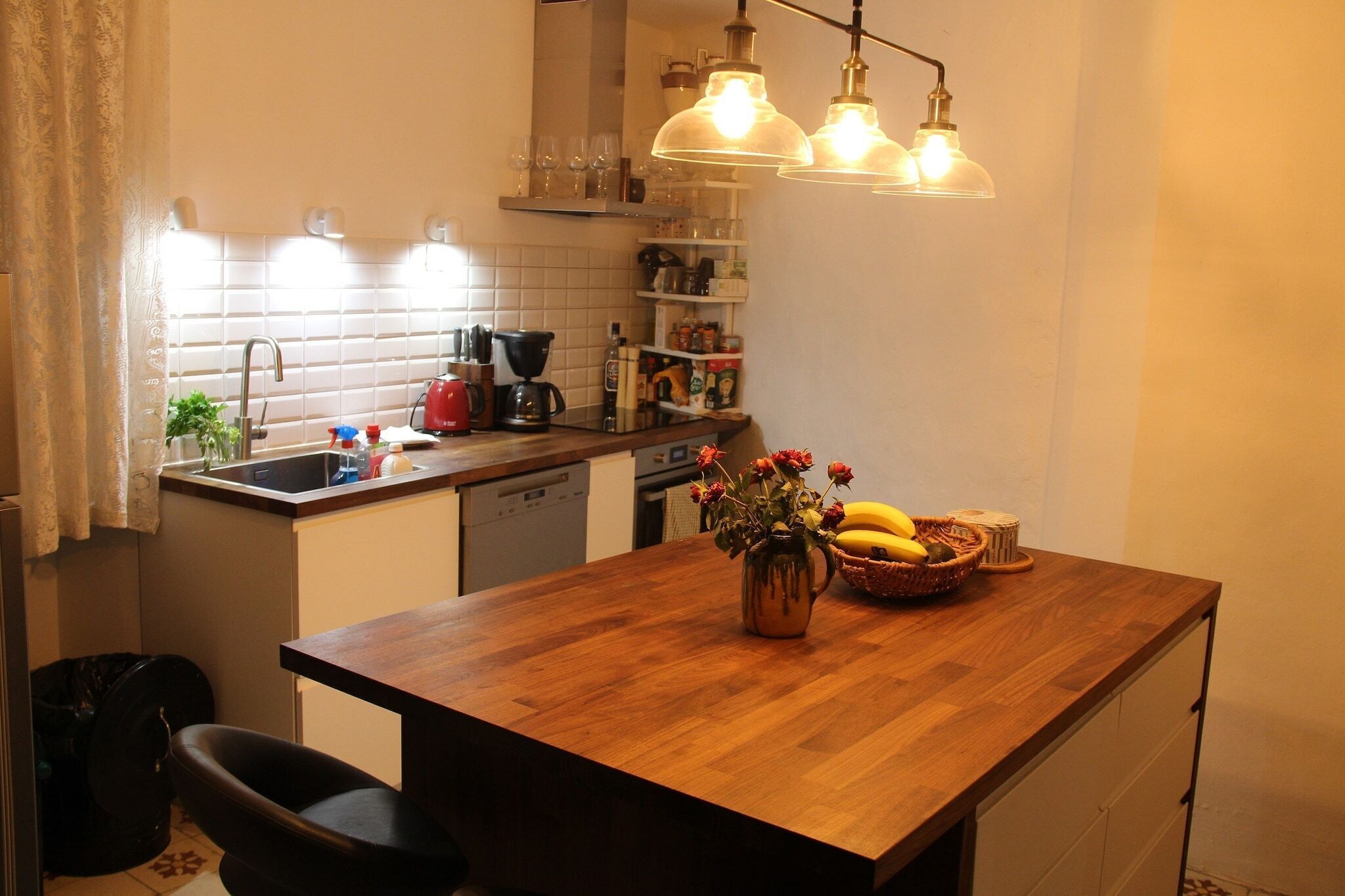 Eine Küche mit Holzarbeitsplatte, Spüle, Kaffeemaschine und einer Vase mit Blumen.