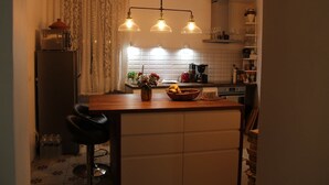 Een kleine keuken met een houten aanrechtblad, een inbouwfornuis en een hanglamp.