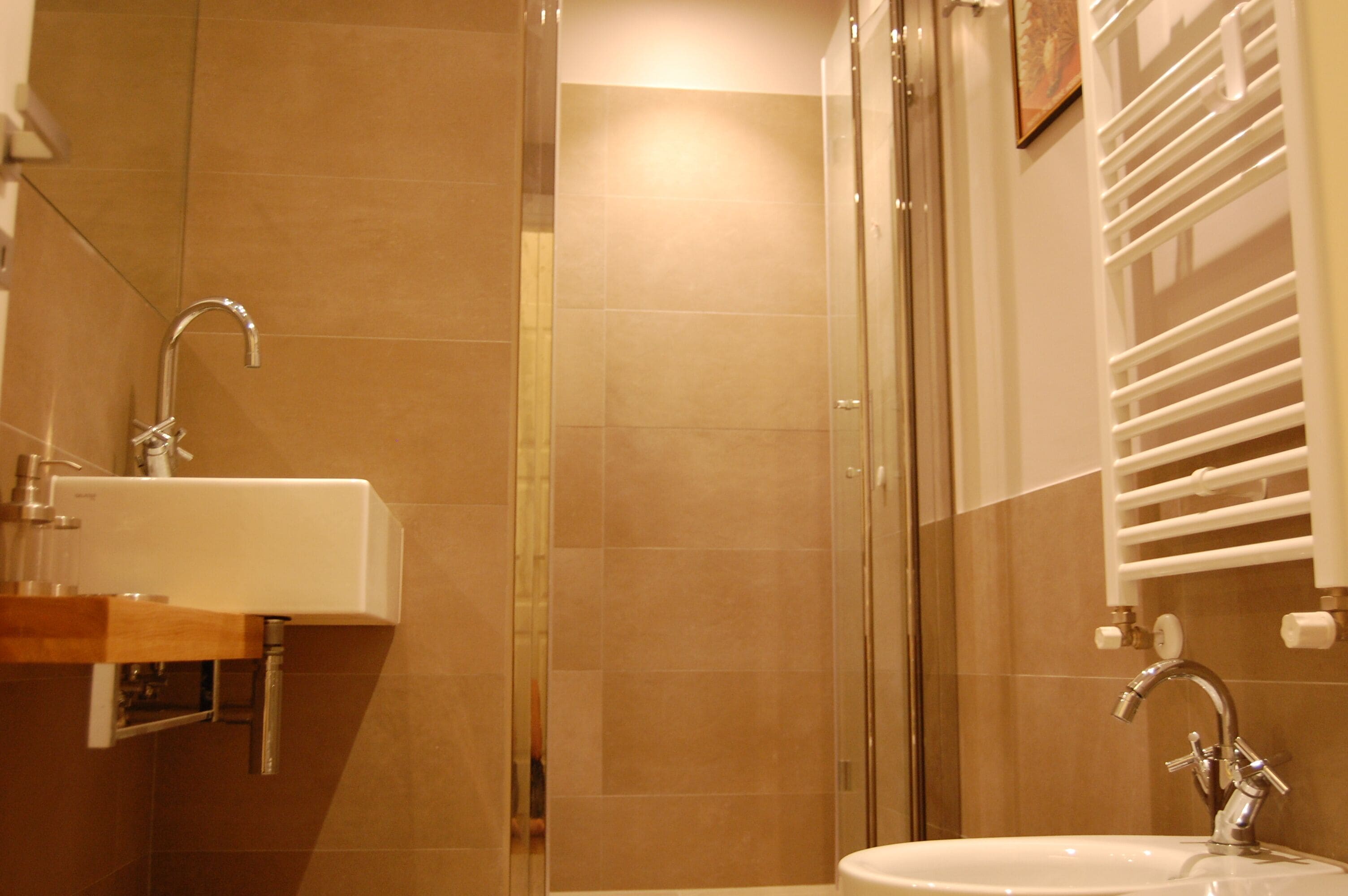 A bathroom with a glass shower enclosure, a sink with a mirror, and a towel rack.