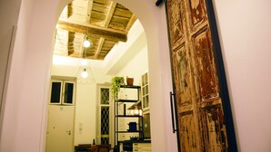 A kitchen with a wooden ceiling, a hanging light fixture, and a rustic door. - Banco 19 b&b  (Rome)