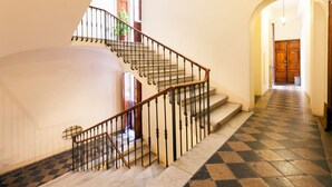 A staircase with a checkered floor and a wooden door at the end. - Banco 19 b&b  (Rome)