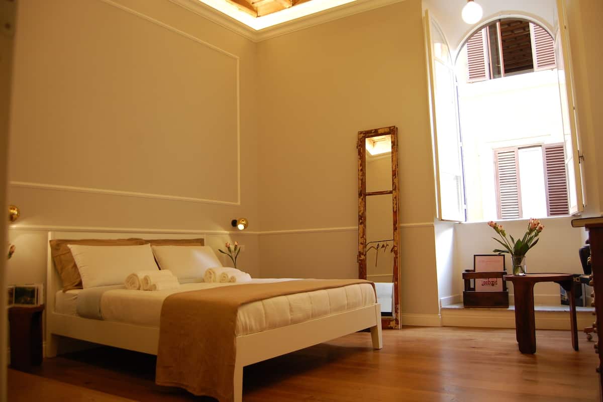Un dormitorio con cama, mesita de noche y espejo.