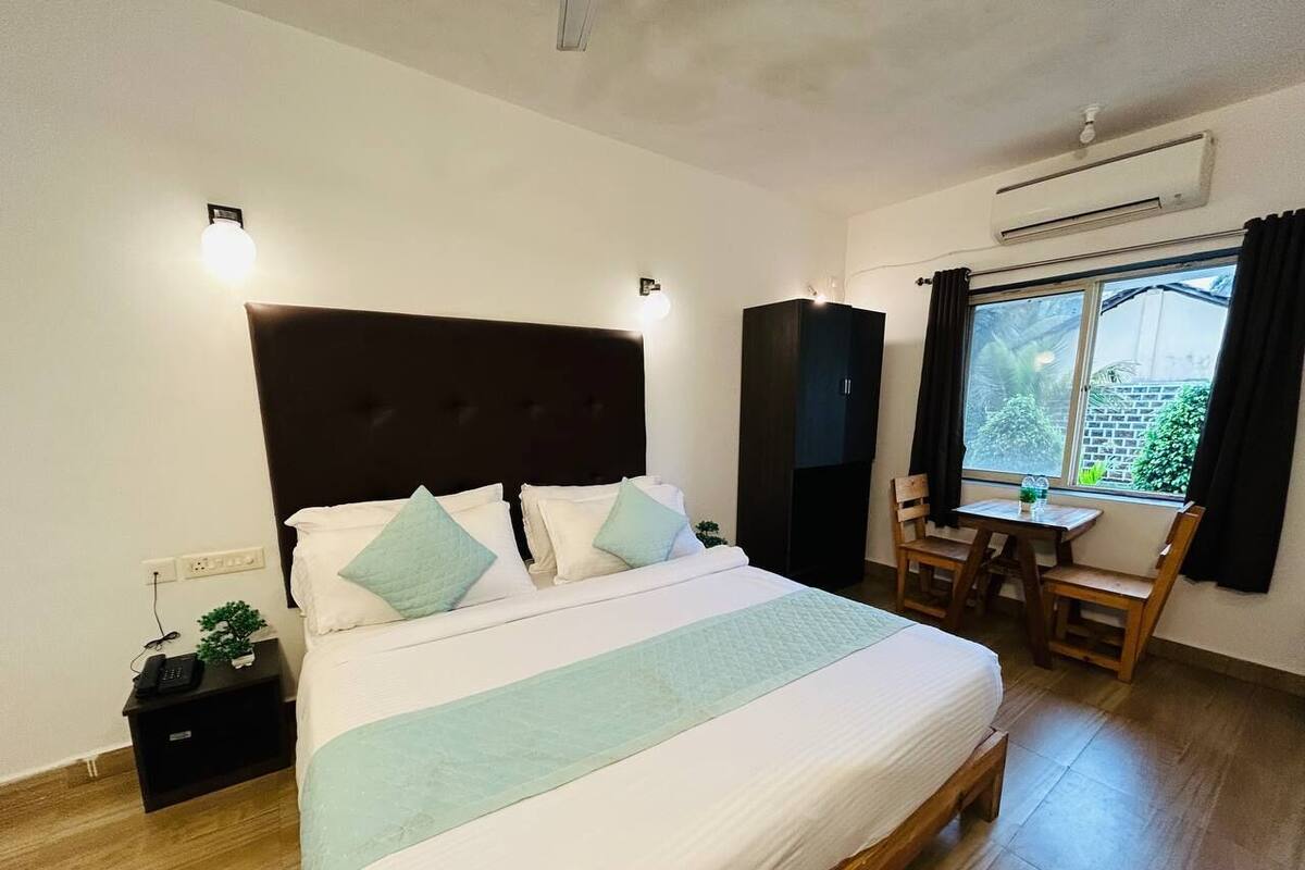 A bedroom with a bed, bedside table, and a window with curtains.