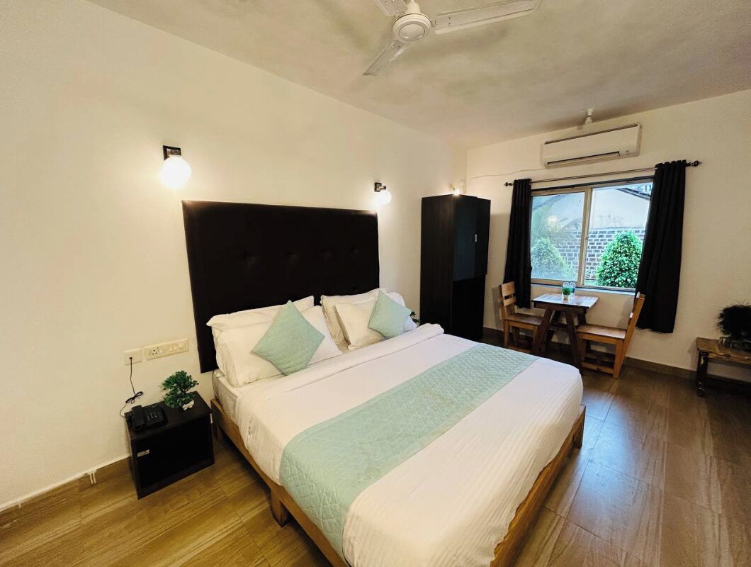 A bedroom with a bed, bedside table, and a window with curtains.