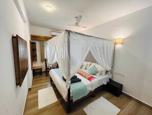 Un dormitorio con cama con dosel, ventilador de techo y mesita de noche.