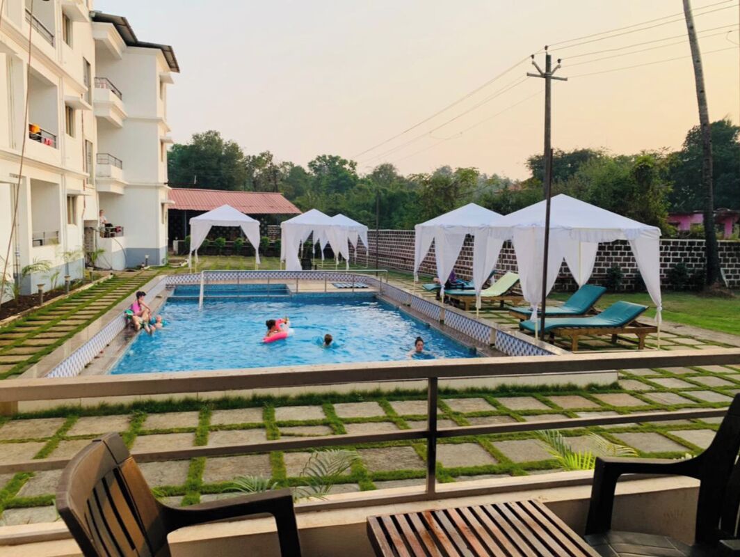 Piscina com deck revestido, rodeada por toldos brancos e espreguiçadeiras.