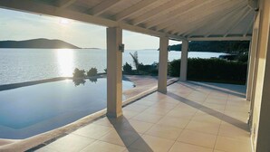 Ein überdachter Infinity-Pool mit Blick auf das Meer und die Hügel.