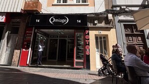 A multi-story building with a storefront labeled 'Omiage' and 'FOTOS' indicating a photography studio.