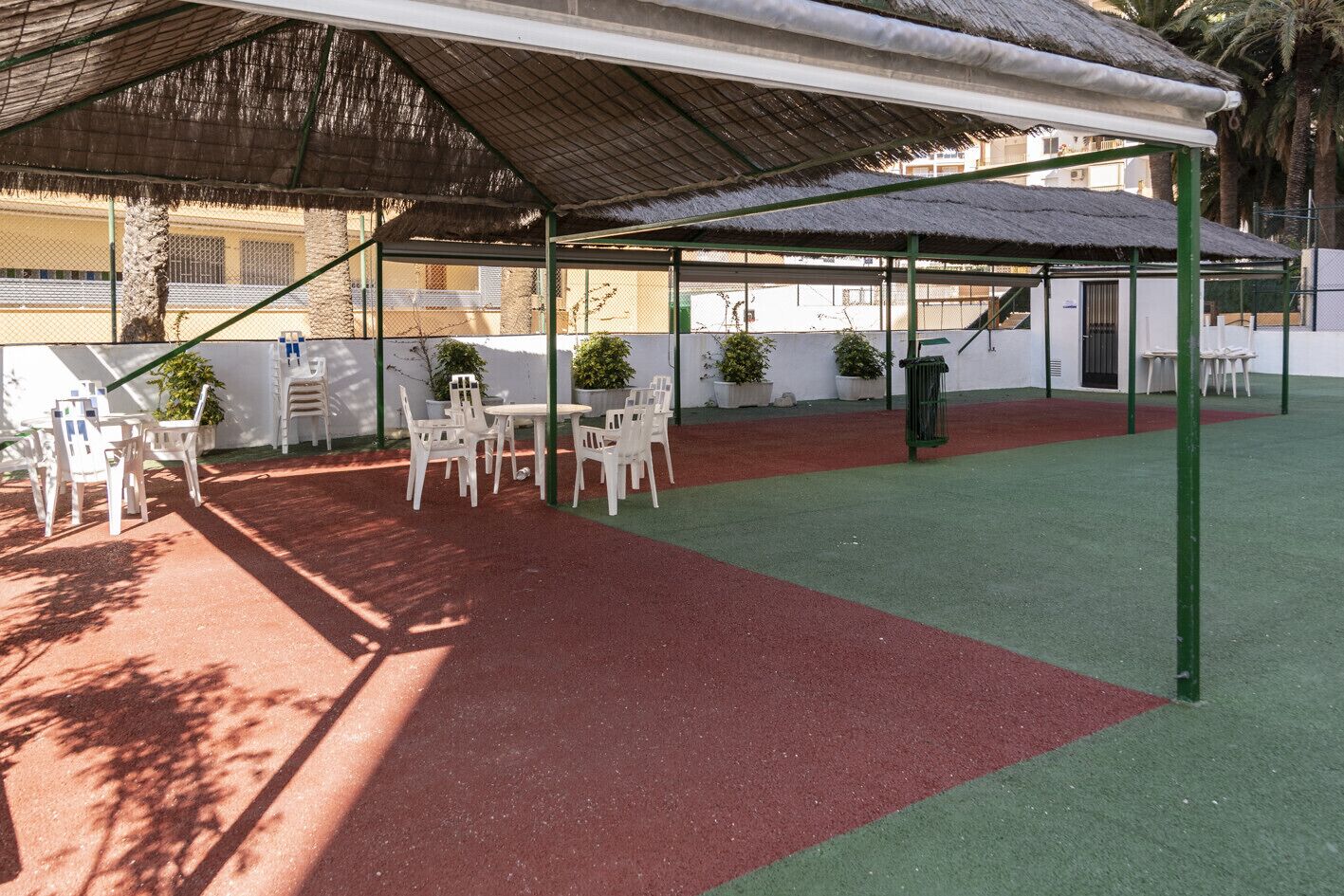 Un espace extérieur aménagé en terrasse, avec un coin salon abrité, des tables et des chaises.
