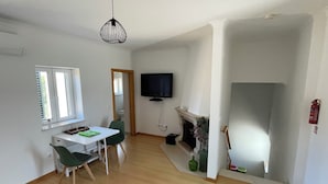 Een moderne woonkamer met een eethoek, een open haard en een televisie.