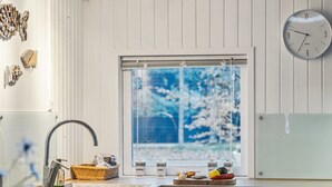 Eine Küche mit Fenster, Spüle, einer Uhr und diversen Küchenutensilien auf der Arbeitsfläche.