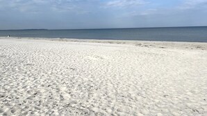 Ein weiter Sandstrand mit blauem Himmel und ruhiger See.