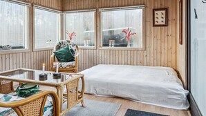 Ein gemütliches Zimmer mit einem Bett, einem Tisch mit Stühlen und großen Fenstern.