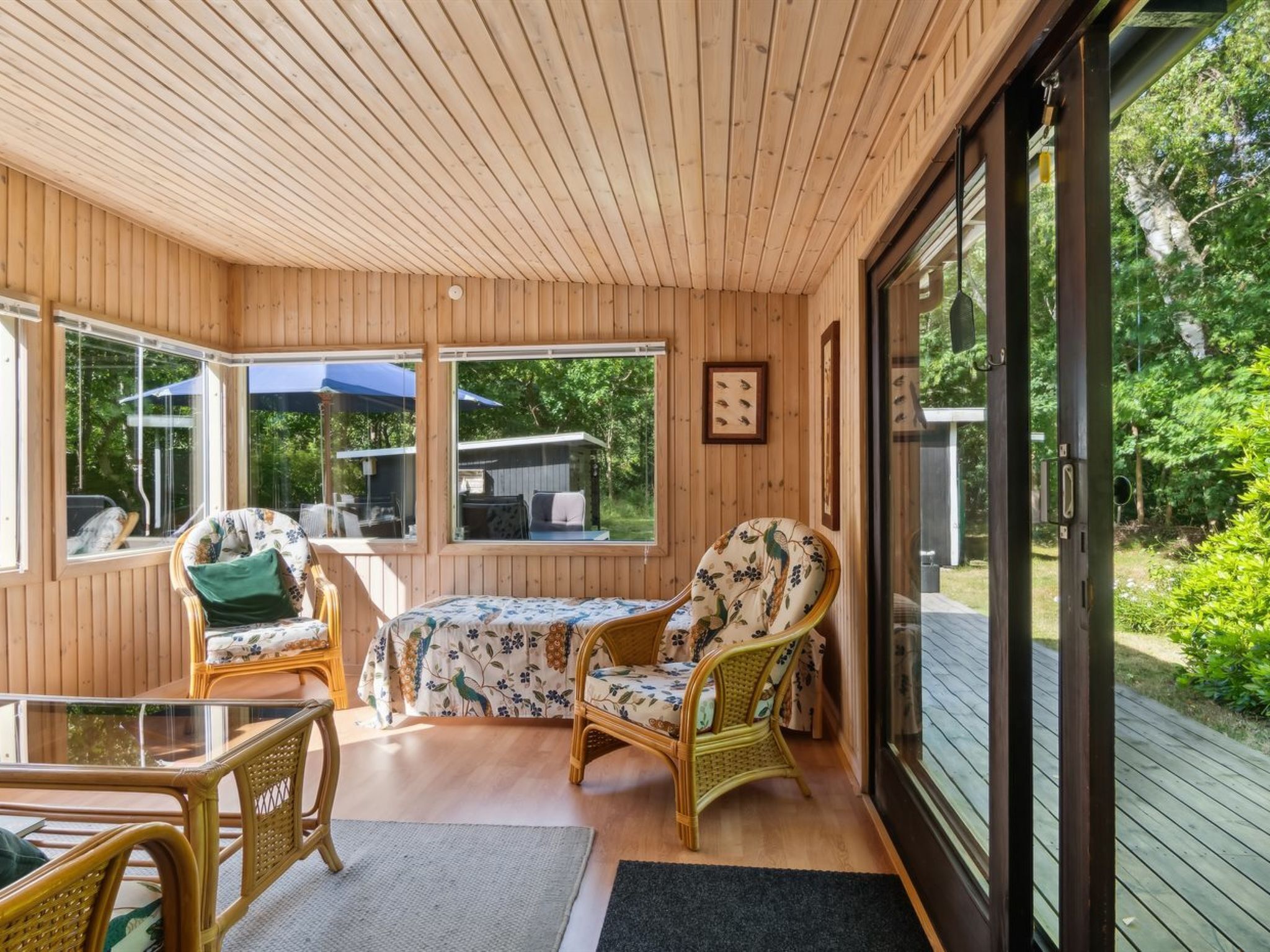 Une pièce chaleureuse, avec des murs en bois, une table et des chaises, de grandes fenêtres et une vue sur l’extérieur.
