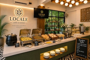 A cafe counter with labeled food options and a sign indicating breakfast buffet availability.