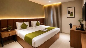 Moderni hotellihuone, jossa on suuri sänky, yöpöytä, työpöytä ja tuoli.