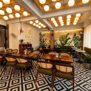 Una cafetería con mesas y sillas de madera, una pared con un logotipo y un suelo con diseño.