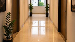A hotel corridor with a polished floor, potted plants, and doors with a number plate. - Room-la Riviera Suites Hotel in Madhap (Hyderabad)