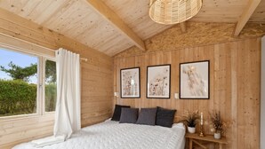 A bedroom with a large bed, wooden walls, and three framed pictures on the wall. - "Marlies" - 300m from the sea by Interhome (Allinge)