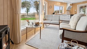 A cozy room with a fireplace, a sofa, a dining table, and a kitchen area. - "Marlies" - 300m from the sea by Interhome (Allinge)