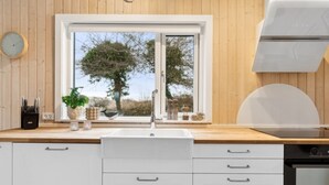 A modern kitchen with a large window, white cabinetry, and a built-in oven. - "Marlies" - 300m from the sea by Interhome (Allinge)
