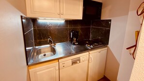 A compact kitchen with a sink, stove, and microwave. - Cozy apartment with terrace, parking and mountain view in La Clusaz (La Clusaz)