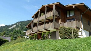 A multi-story building with balconies, surrounded by greenery and a mountainous backdrop. - Cozy apartment with terrace, parking and mountain view in La Clusaz (La Clusaz)