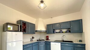Una cocina compacta con armarios azules, un refrigerador blanco, lavavajillas, estufa y microondas.