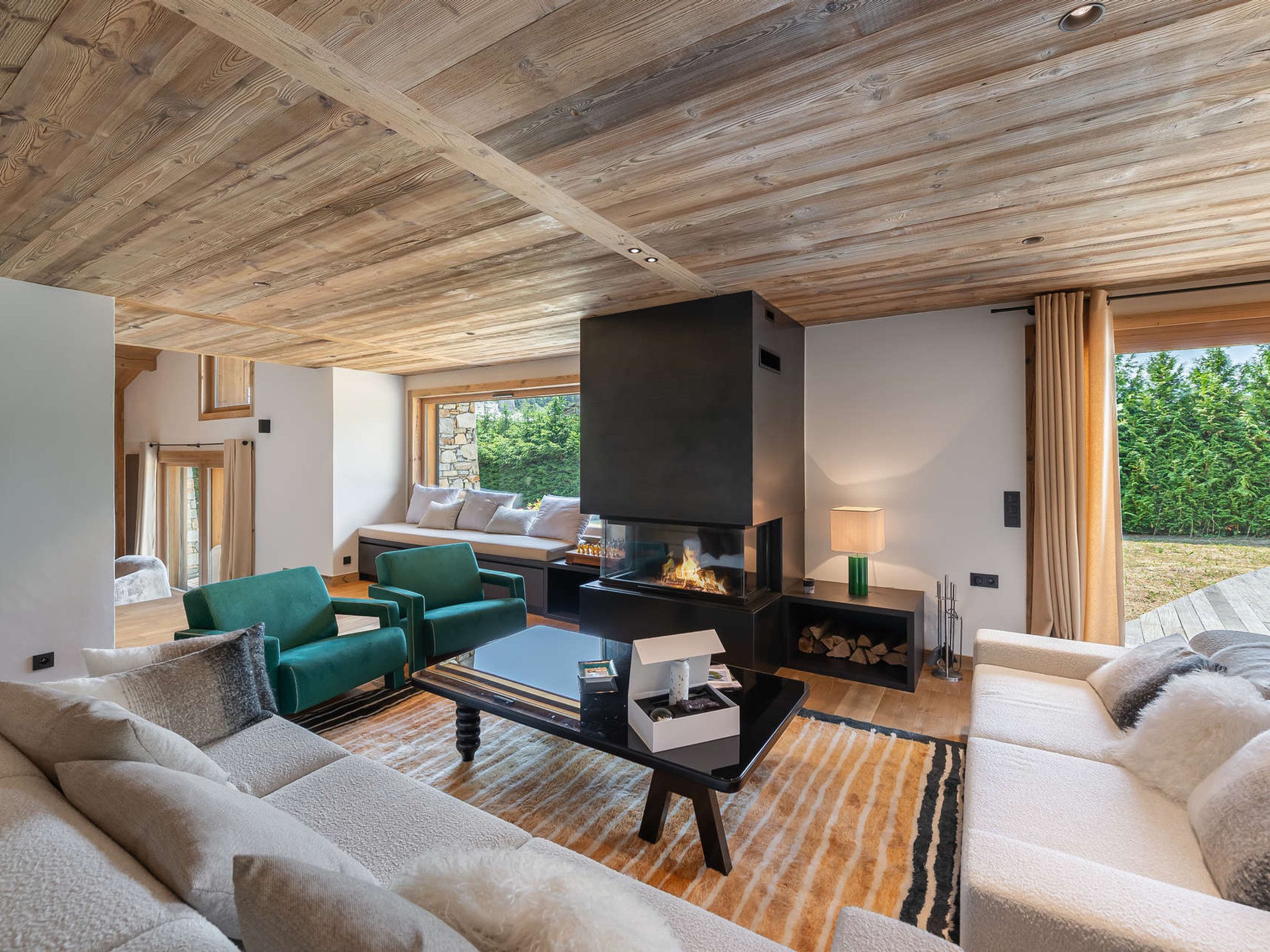 Ein modernes Wohnzimmer mit Kamin, grünen und weißen Sofas und einer Steinwand.