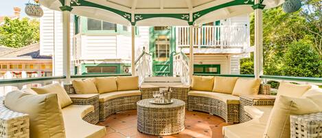 Un espace extérieur aménagé, abrité et doté de mobilier en osier et d’une table basse centrale.
