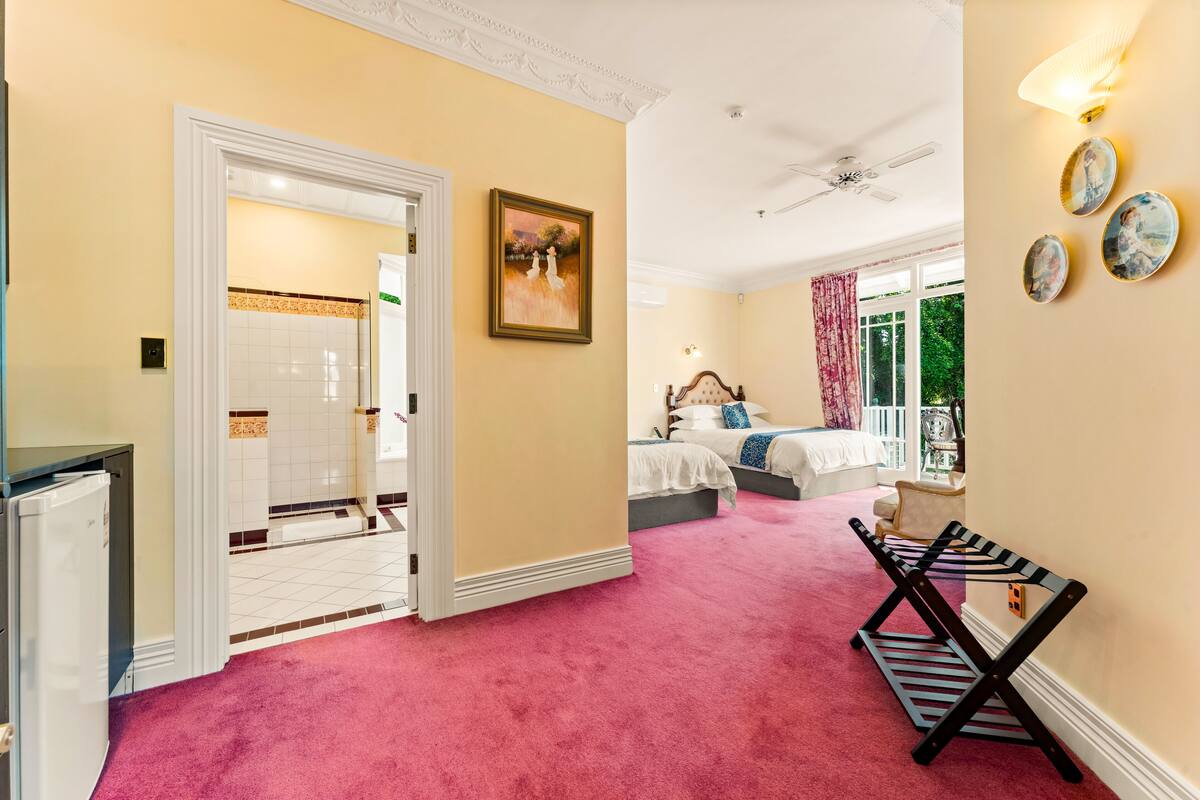 A bedroom with a bed, a vanity, and a bathroom with a shower and toilet.