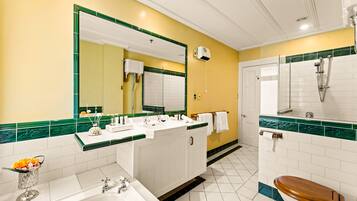 A bathroom with a large mirror, white sink, and a shower area.
