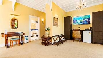A room with a piano, a TV, a refrigerator, and a dining table.