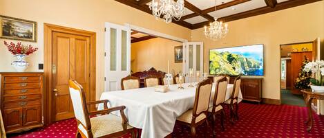A dining room with a red carpet, wooden furniture, and a chandelier.