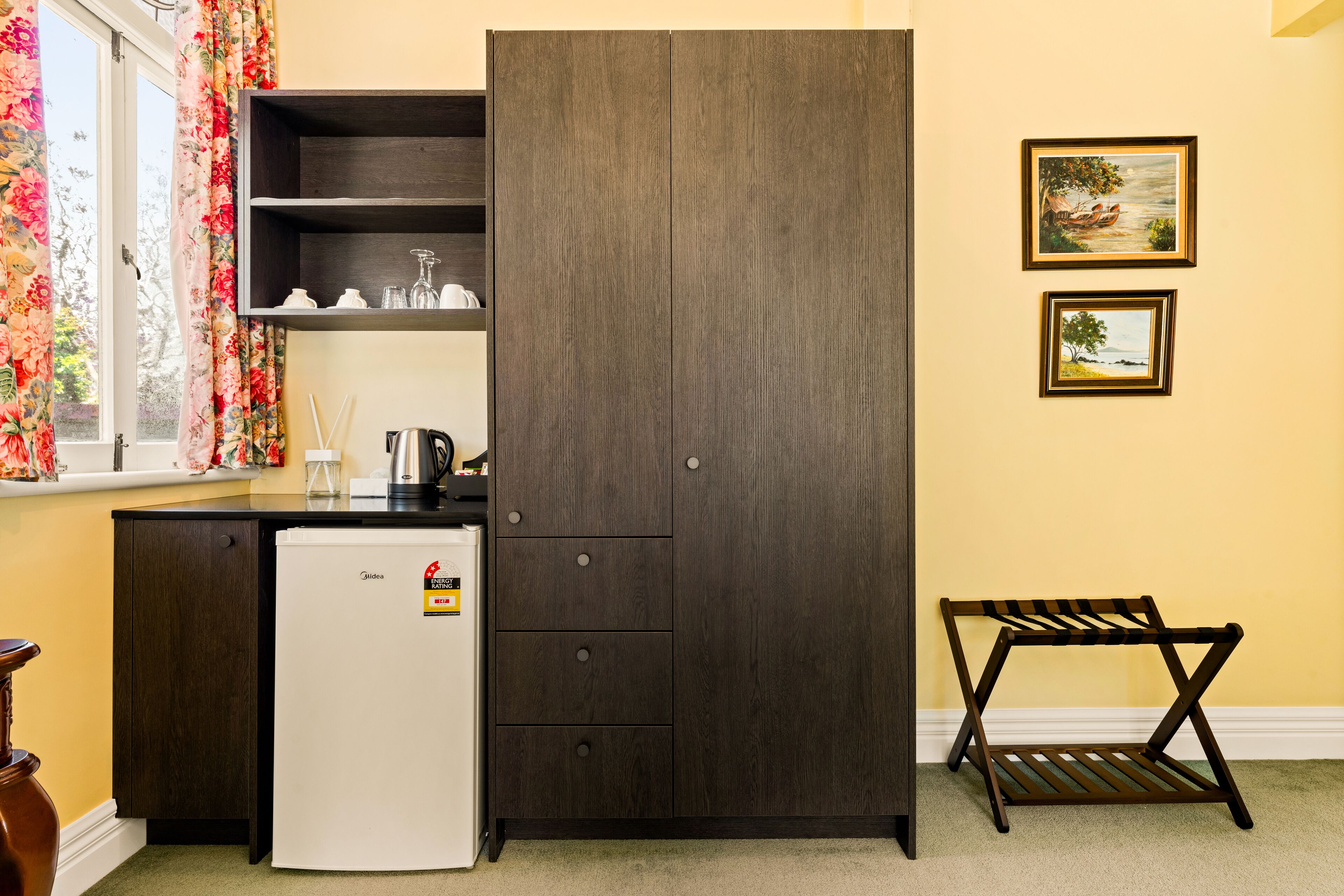 Une cuisine compacte comprenant un réfrigérateur, un meuble en bois foncé et une petite table.